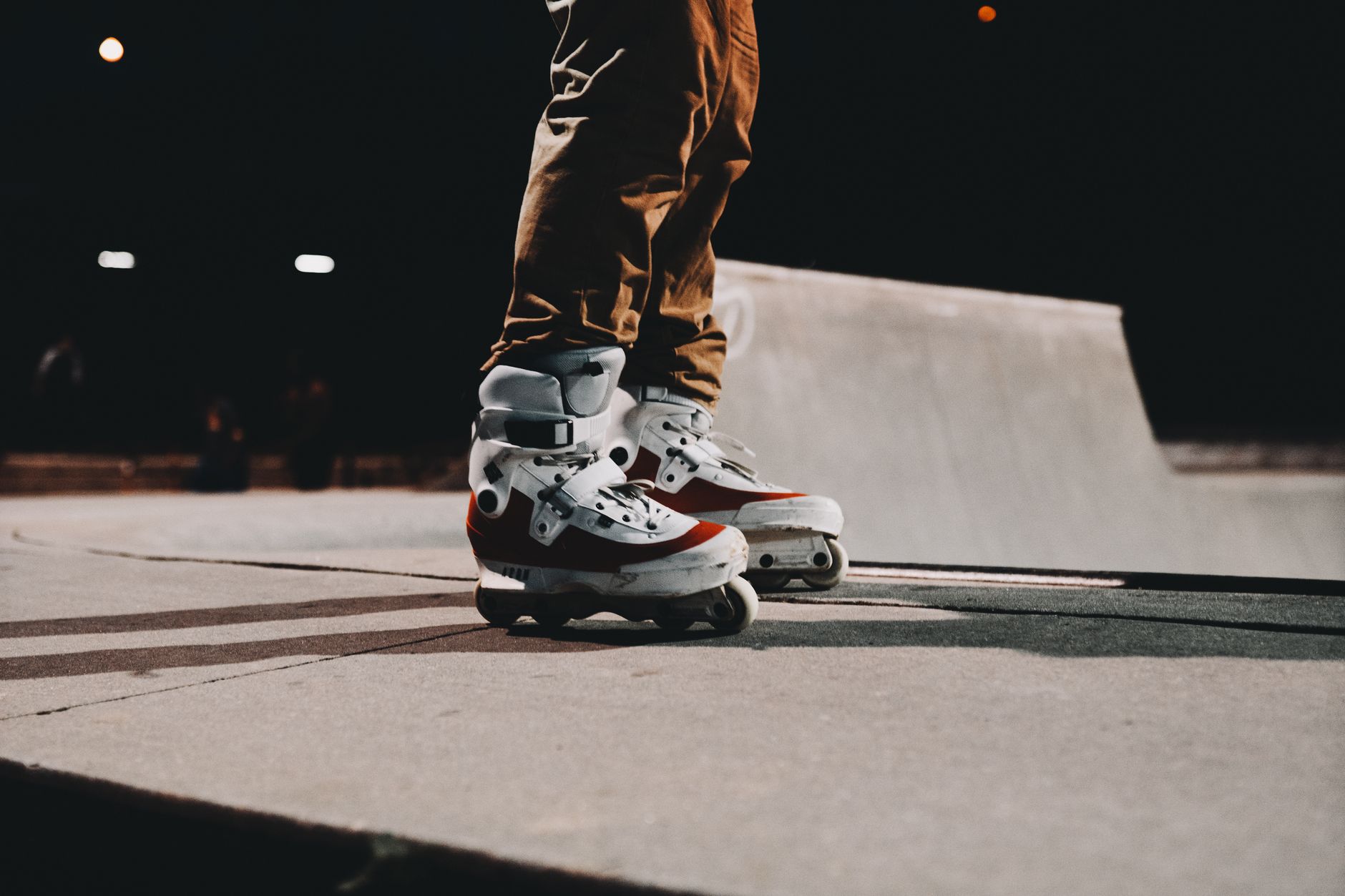 Rolkarz w rolkach inline na betonowej nawierzchni skateparku nocą