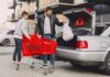 Mężczyzna z chłopcem pakują zakupy do bagażnika auta przed podróżą