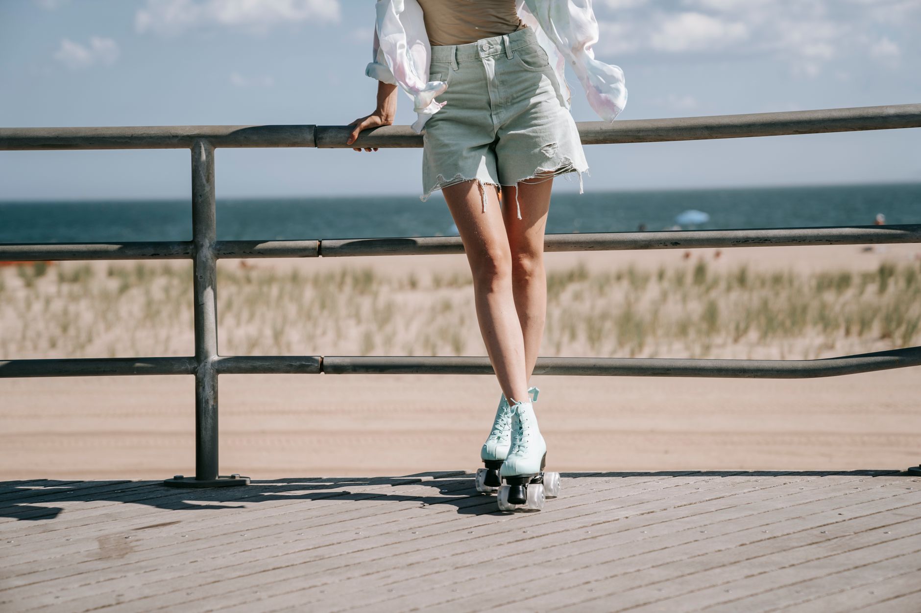 Młoda kobieta na rolkach jedzie promenadą przy plaży w słońcu