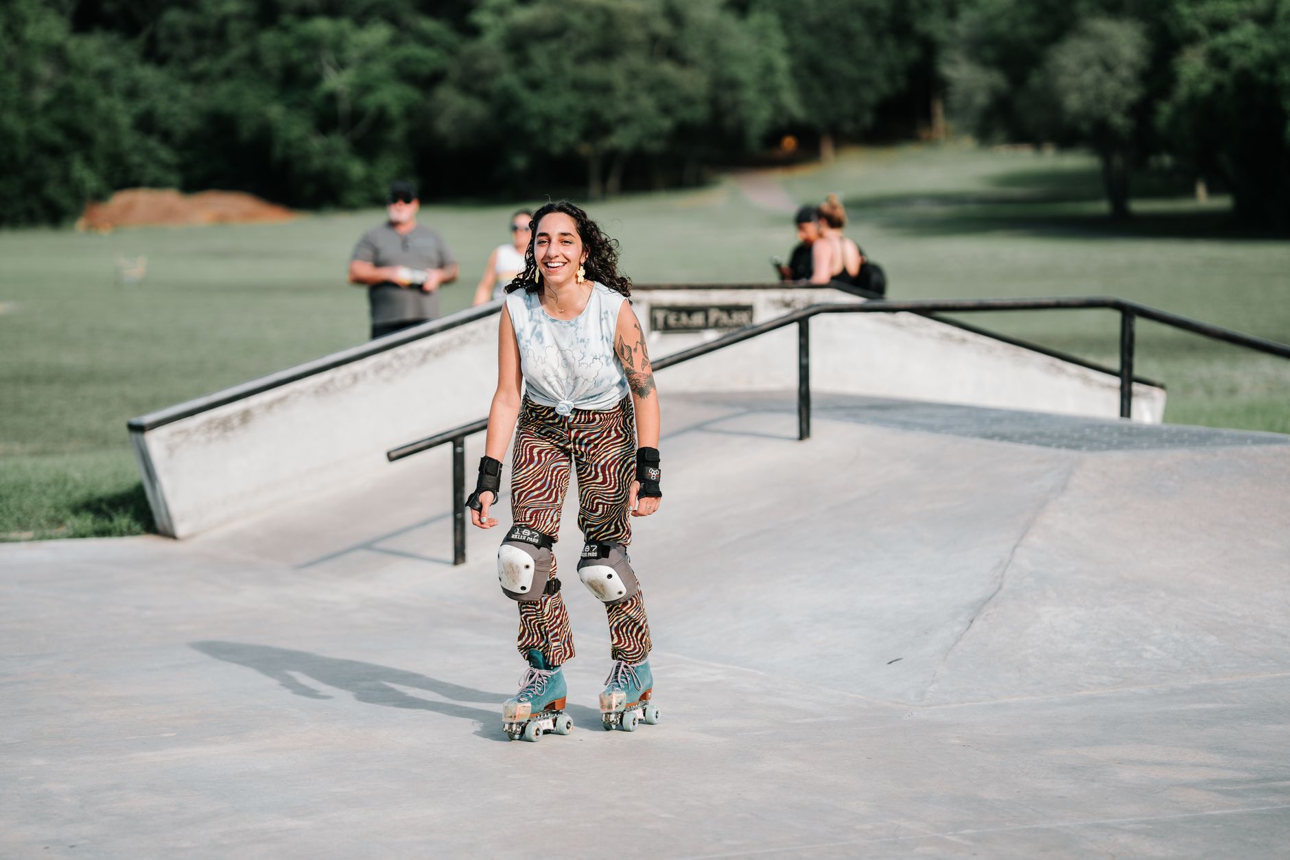 Uśmiechnięta kobieta na rolkach w ochraniaczach w skateparku w słońcu